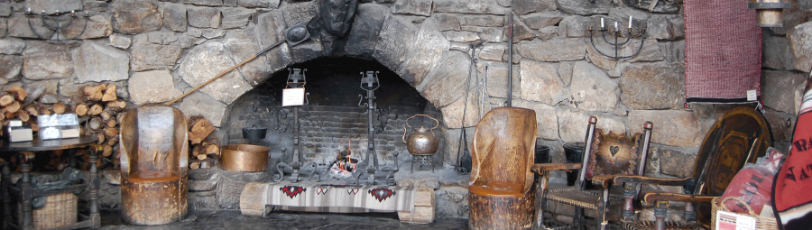 A stone hearth fireplace with two wooden seats set to the right.